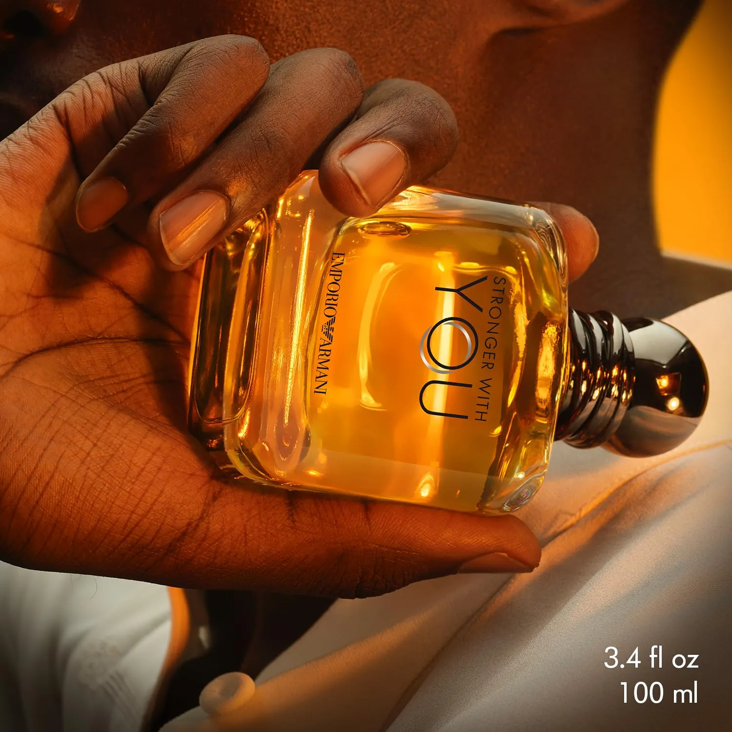 Armani Stronger With You bottle held in warm light