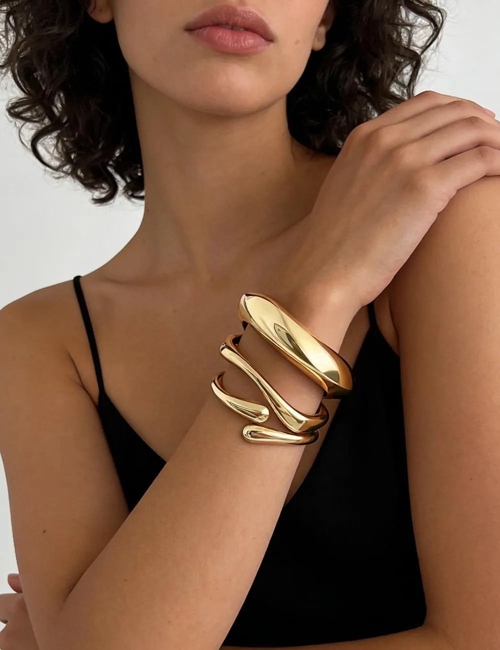 Chunky gold bangle bracelets worn with a black outfit