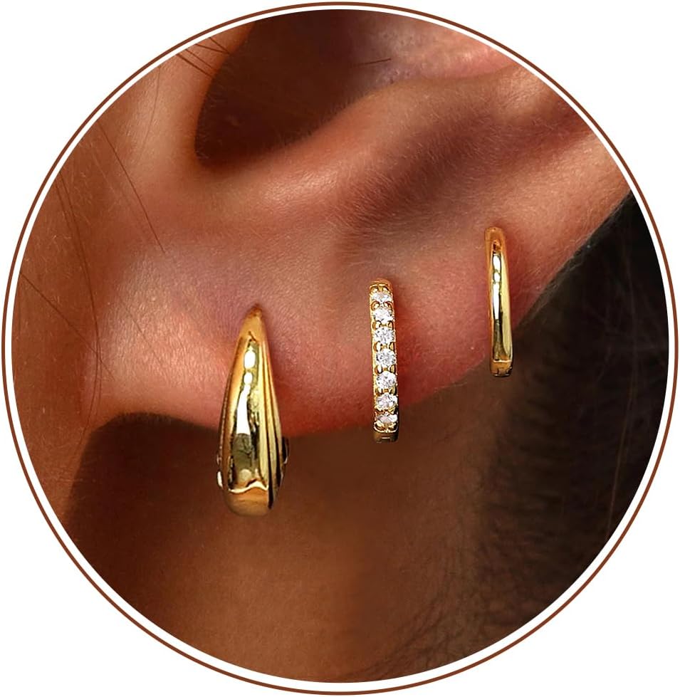 Small gold huggie hoop earrings worn on an ear